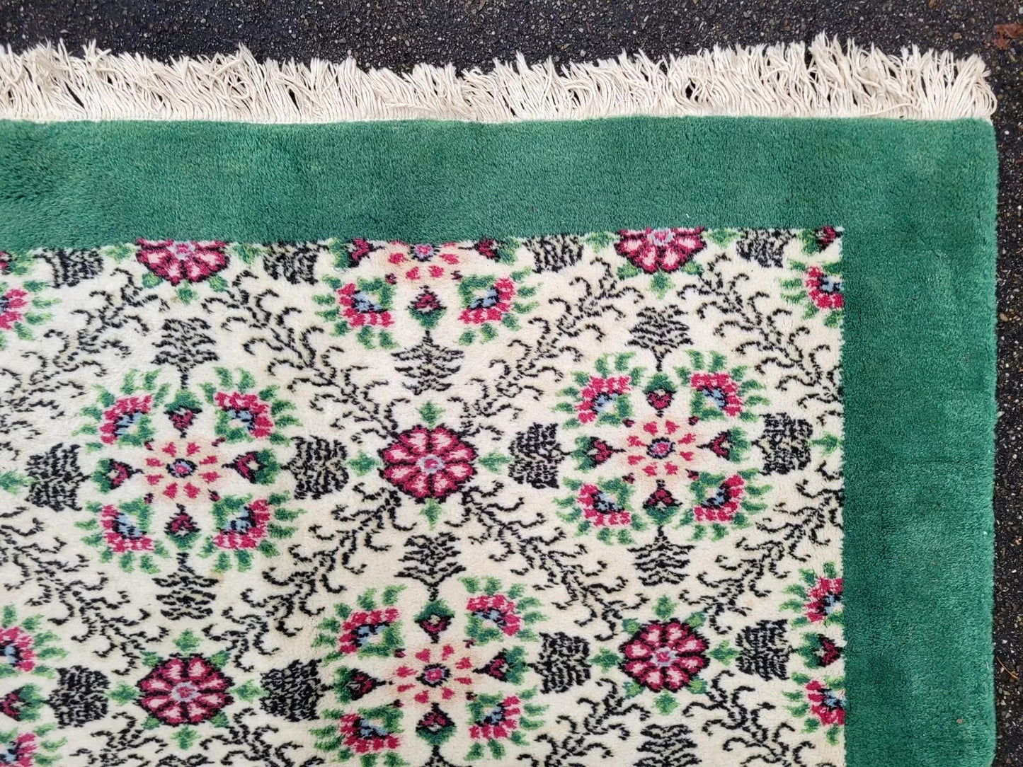 Antique rug with a rich green border framing the central field.
