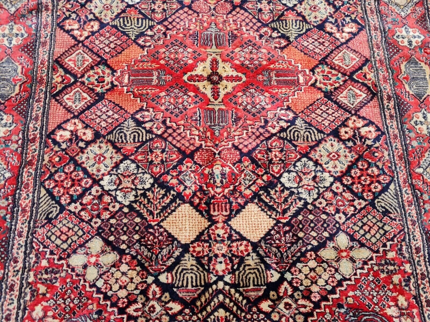 Hand-knotted Persian rug showing a dense symmetrical pattern.