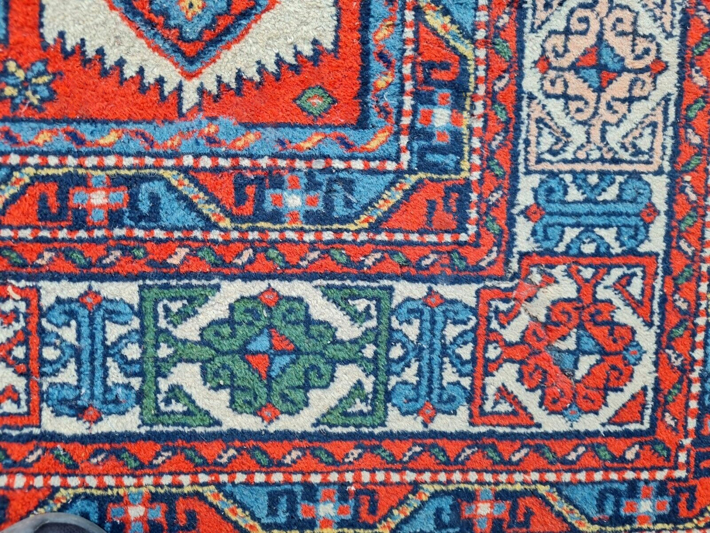 rich red background of Kazak rug with bold diamond shapes