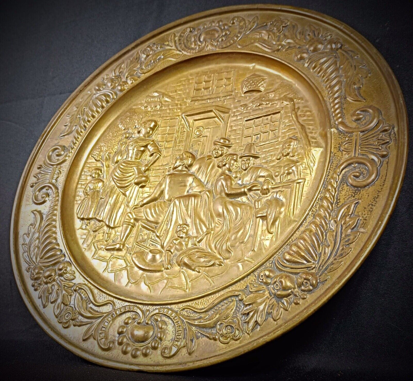 Close-up of intricate repoussé details on a brass plate
