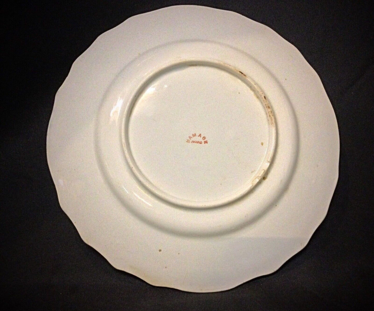 Back view of the antique faience plate showing signs of age-related wear.