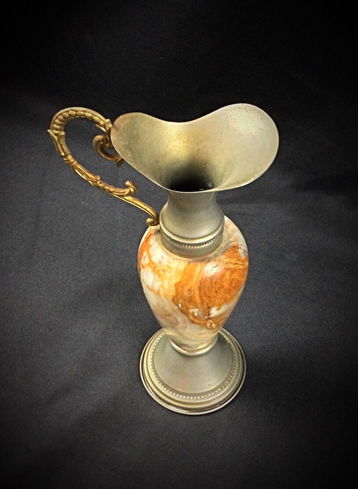 Artistic onyx and pewter vase placed on a wooden shelf
