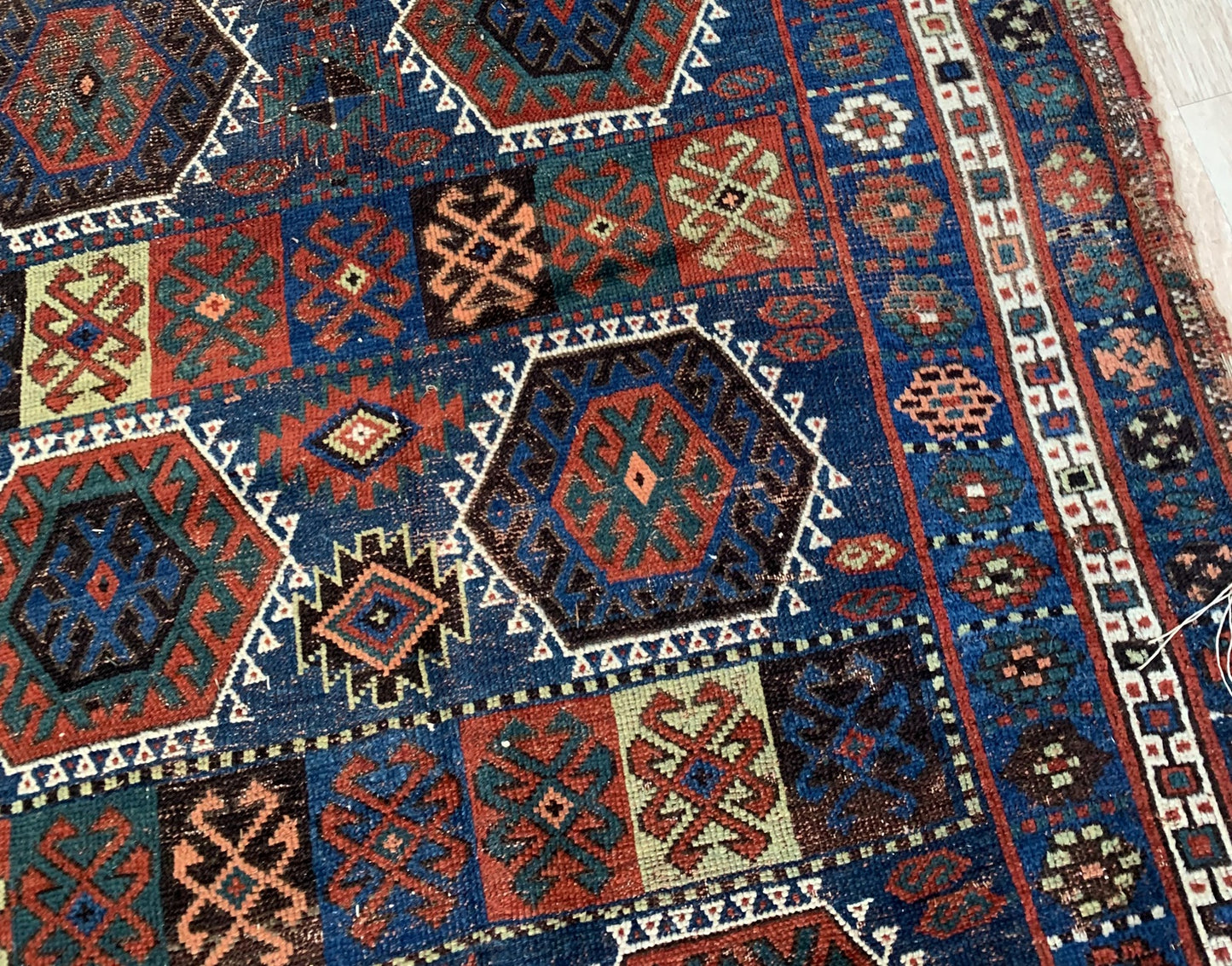 Close-up of a patterned rug with geometric designs in blue, red, and brown.