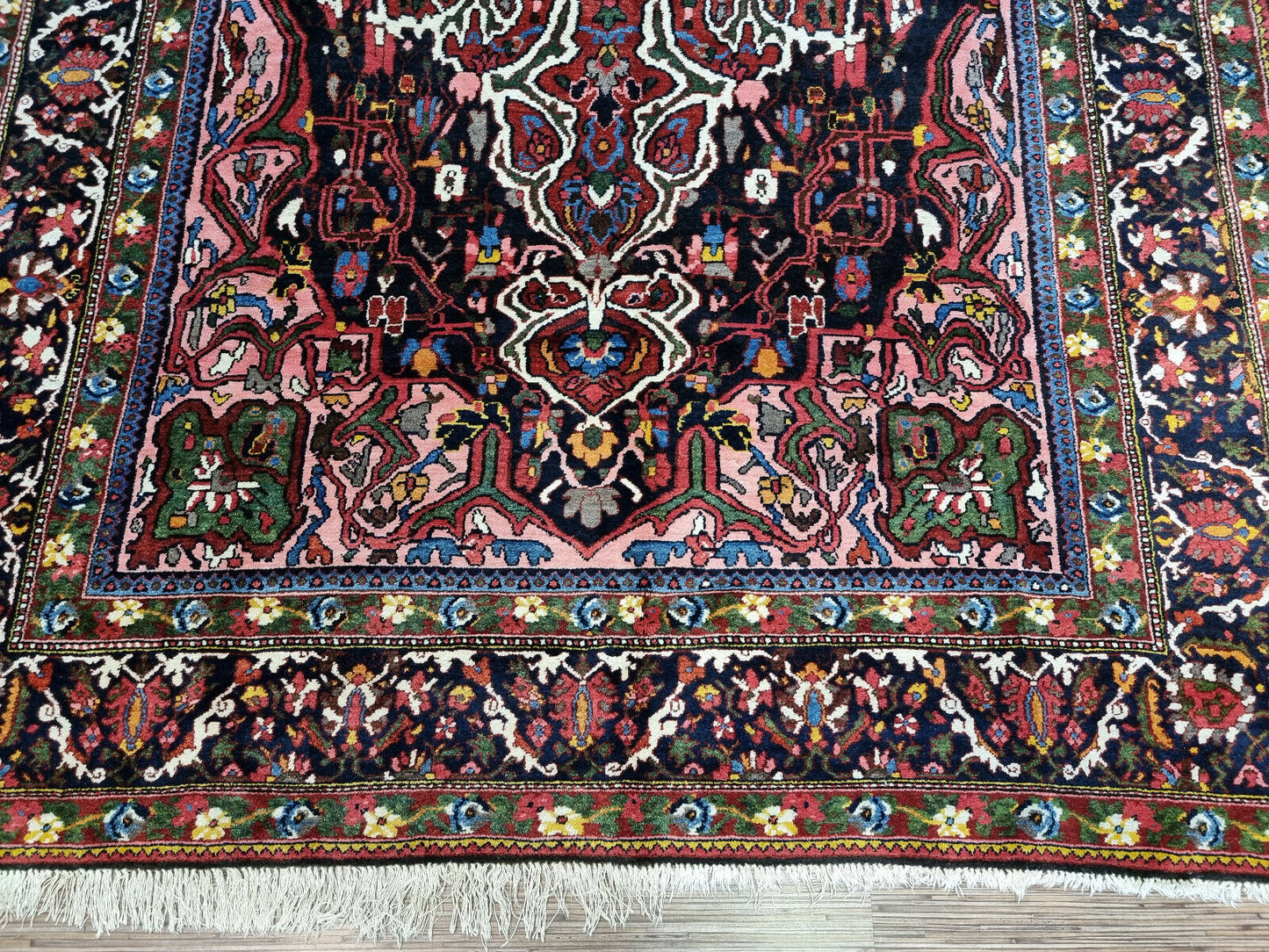 Close-up of rich tapestry of colors on Handmade Antique Persian Bakhtiari Rug - Detailed view showcasing the vibrant hues including deep reds, vibrant blues, lush greens, and subtle creams.