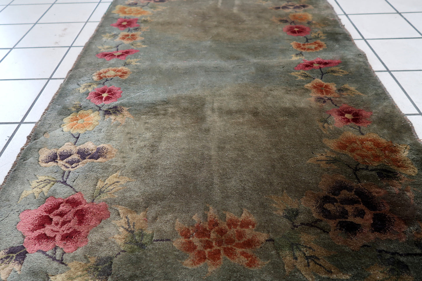 Handmade antique Art Deco Chinese rug in green color and floral design. The rug is from the end of 20th century in original condition, it has some age discolorations and signs of wear.