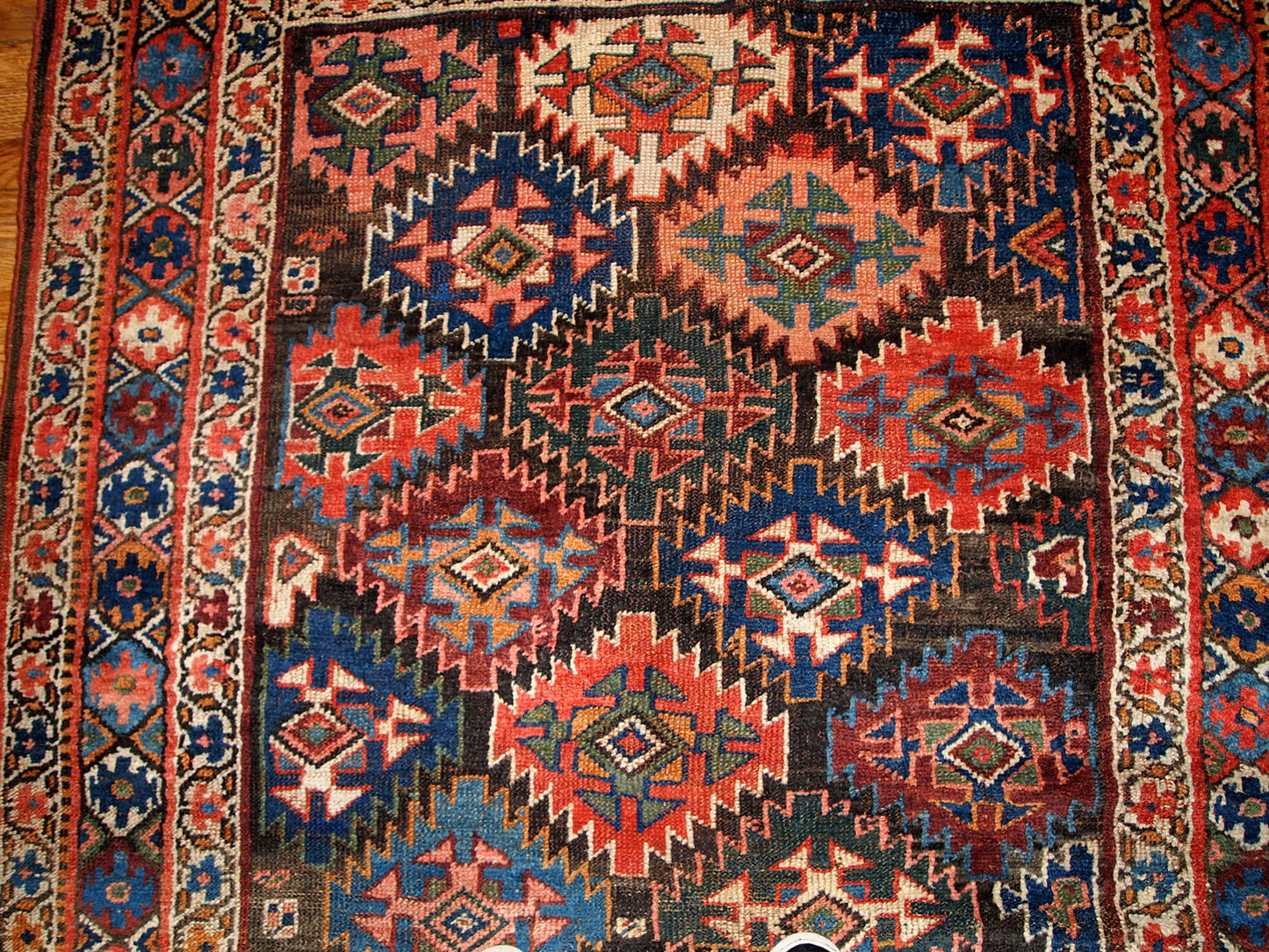 Antique Persian Kurdish rug in chocolate brown background color and repeating pattern. This rug has Jaff Kurdish design. It is in original good condition.