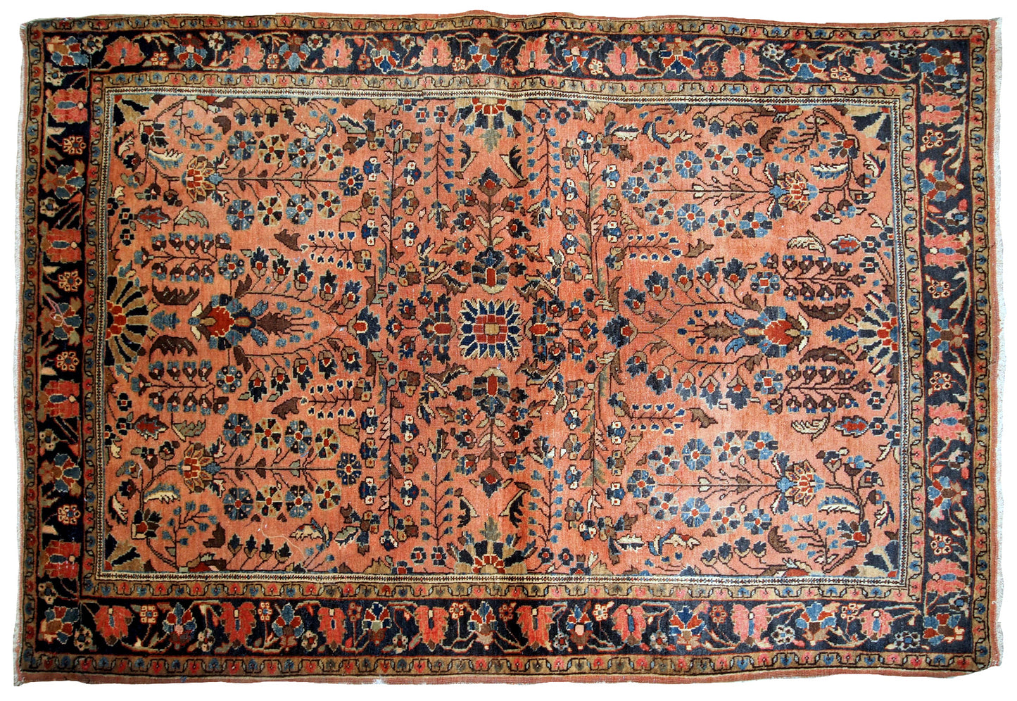 Handmade antique Sarouk rug in salmon shade. The rug is in original good condition from the beginning of 20th century.