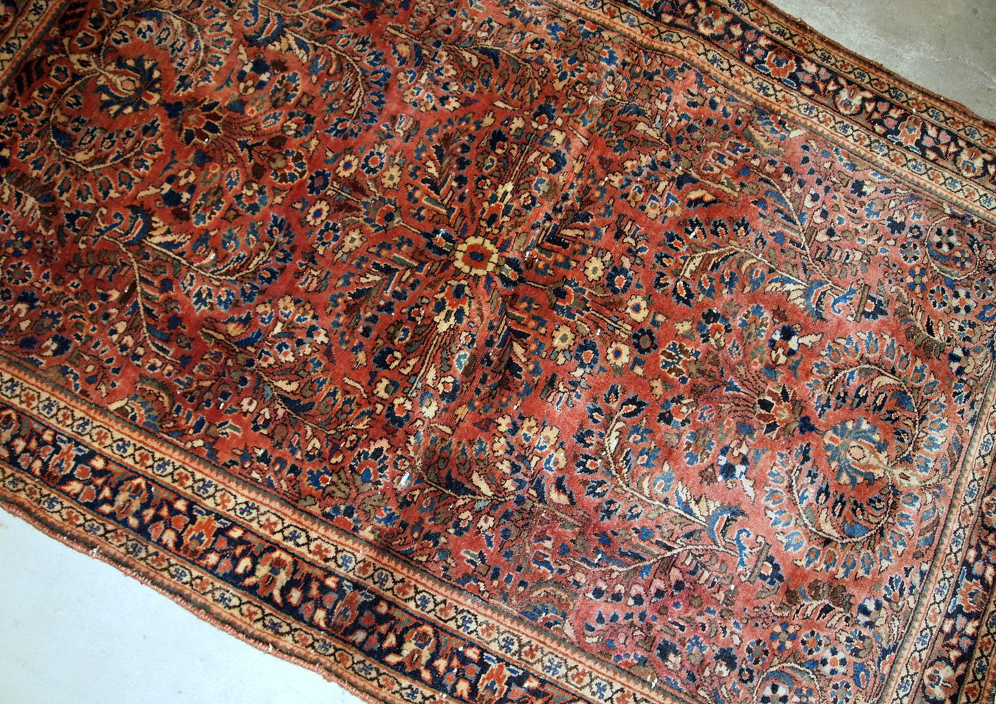 Hand-weaved antique Sarouk rug from the beginning of 20th century. The rug is in original good condition, made in classic floral design.
