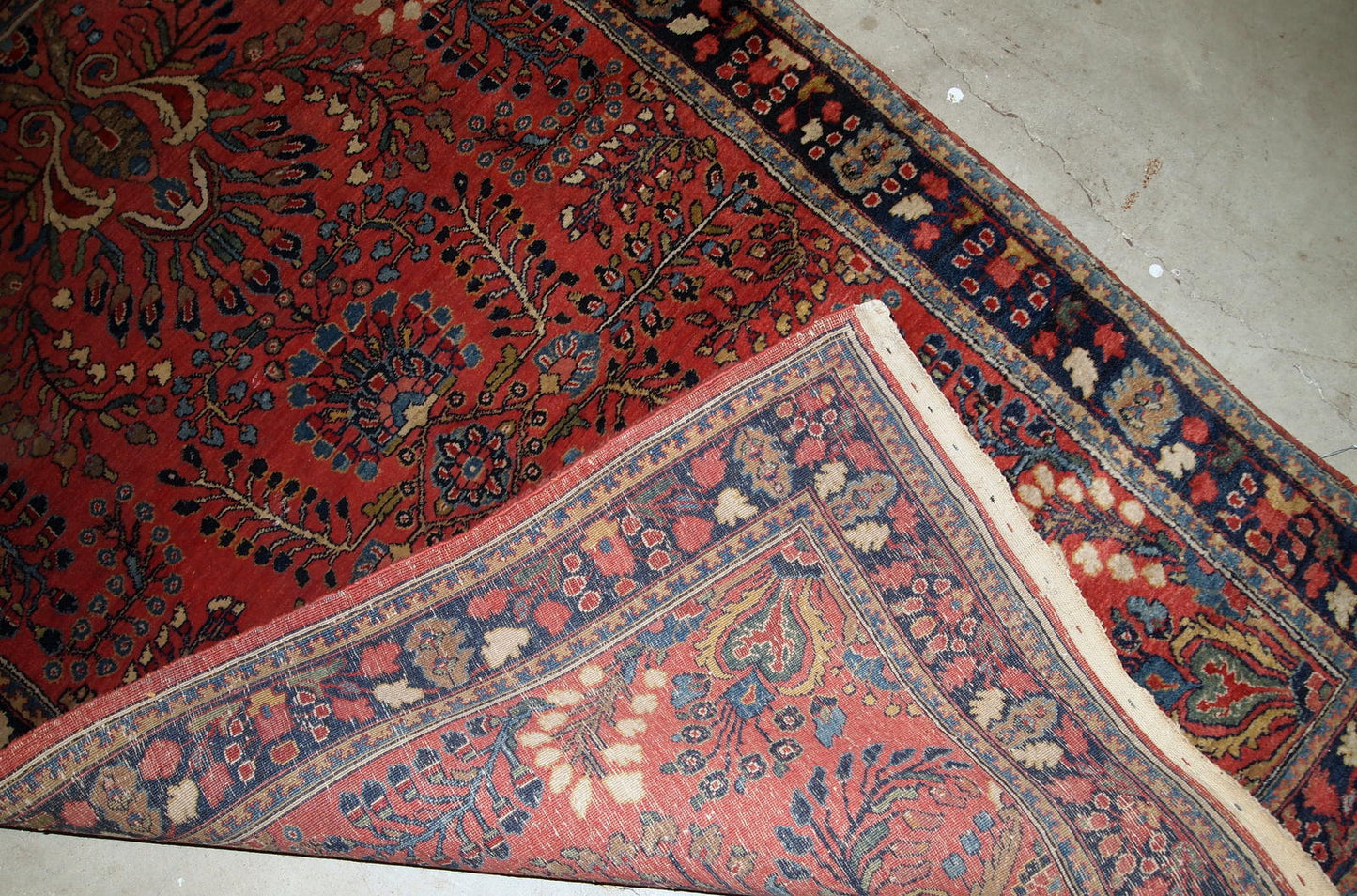 Handmade antique Sarouk rug in red color. The rug is from the beginning of 20th century in original good condition.