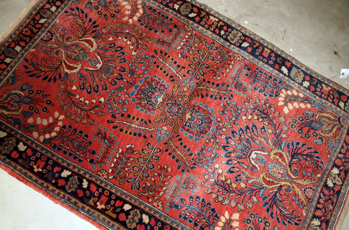 Handmade antique Sarouk rug in red color. The rug is from the beginning of 20th century in original good condition.