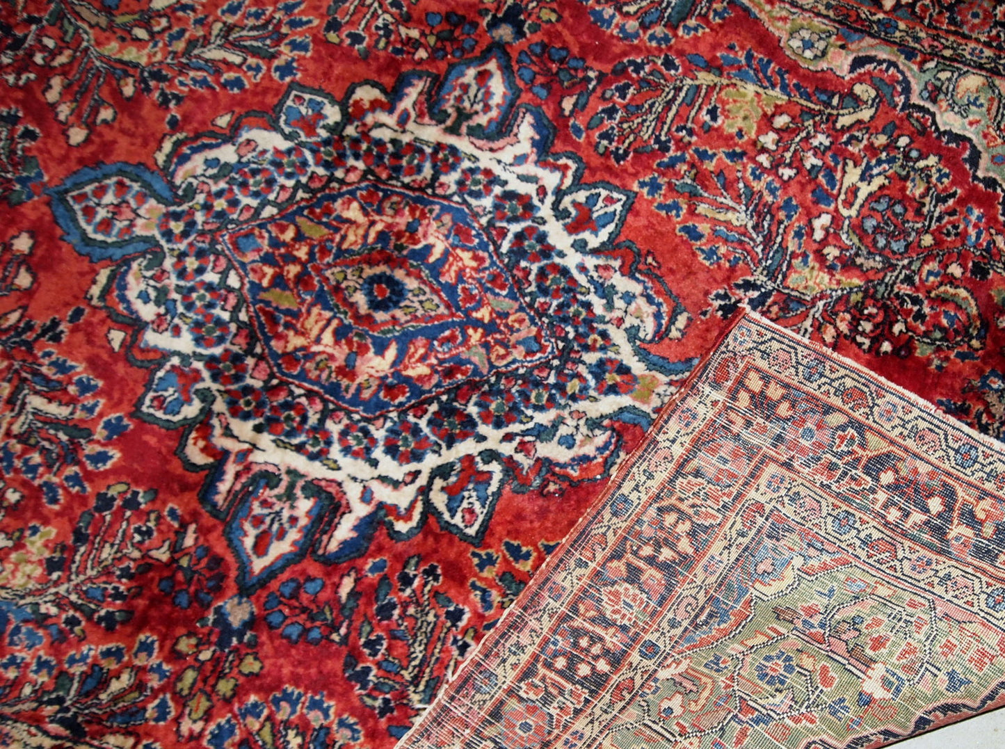 Handmade antique Sarouk rug in red color. The rug is from the beginning of 20th century in original good condition.