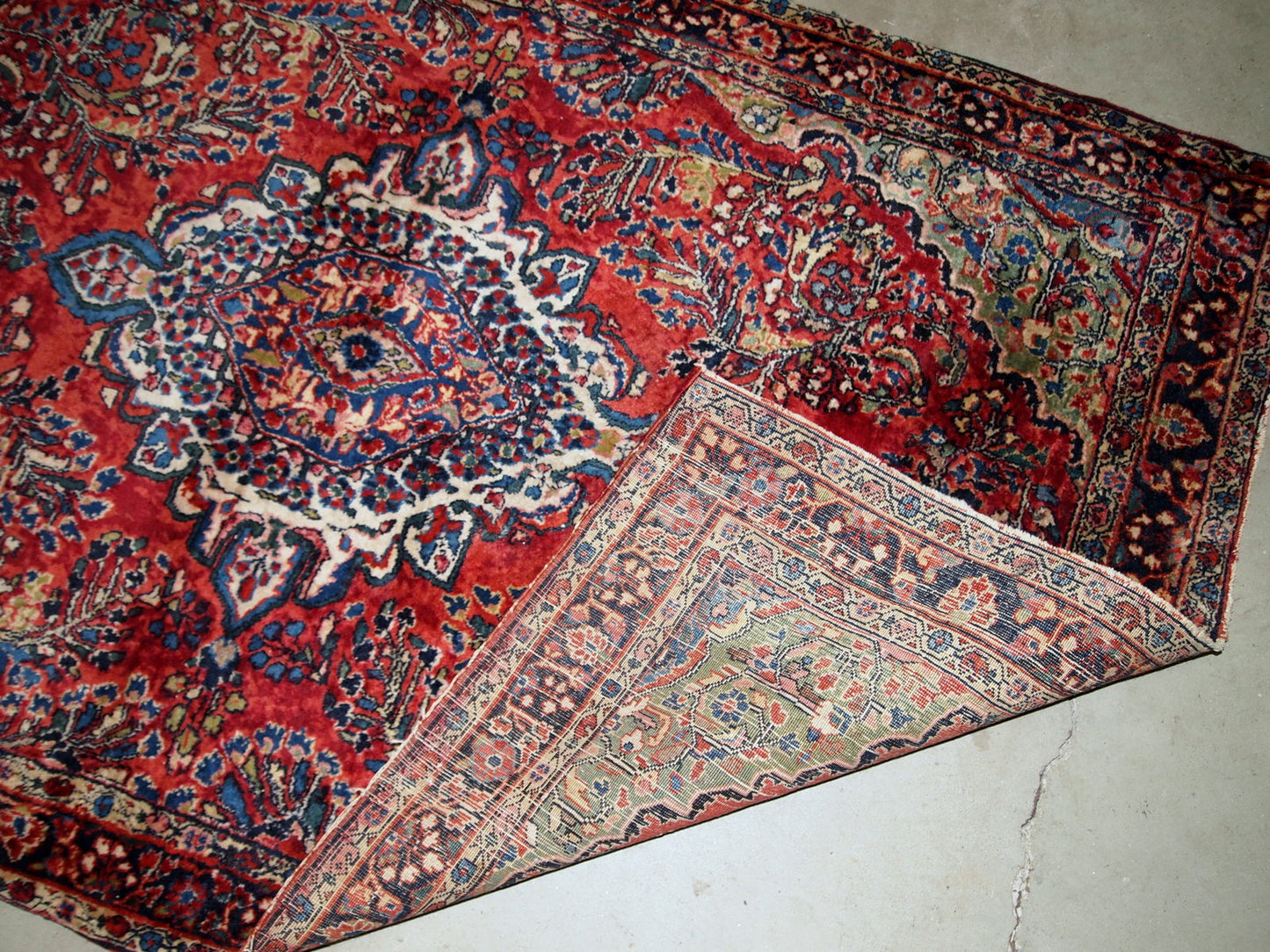 Handmade antique Sarouk rug in red color. The rug is from the beginning of 20th century in original good condition.