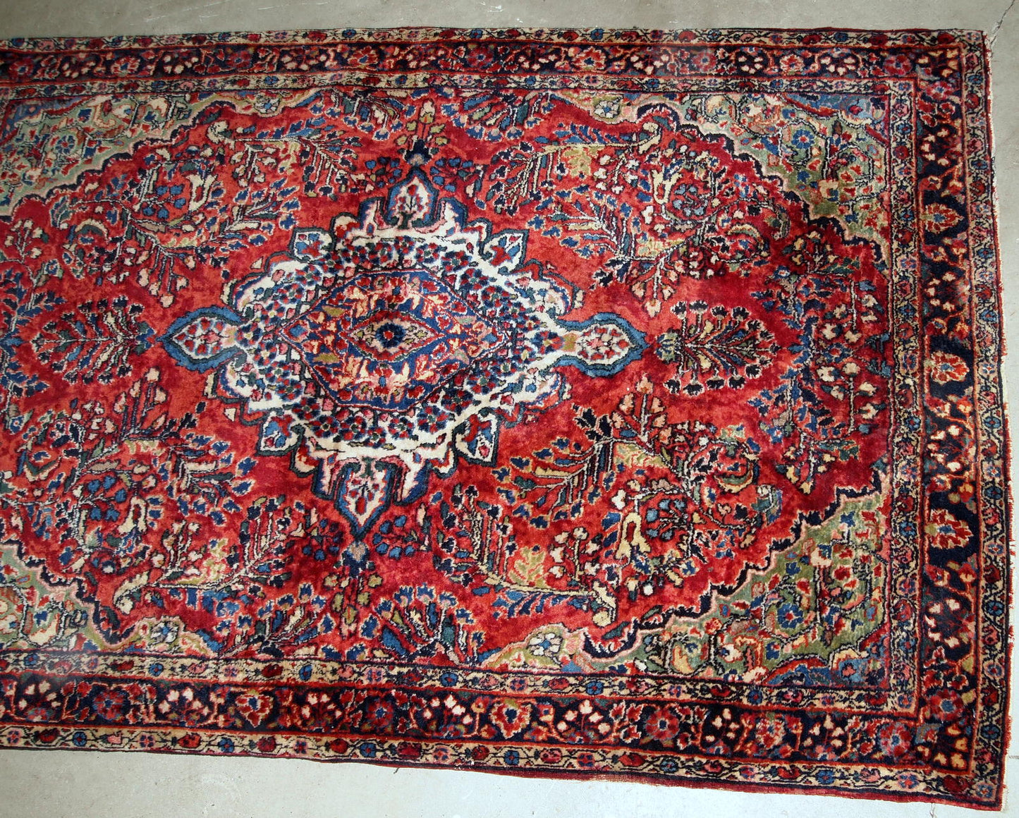 Handmade antique Sarouk rug in red color. The rug is from the beginning of 20th century in original good condition.