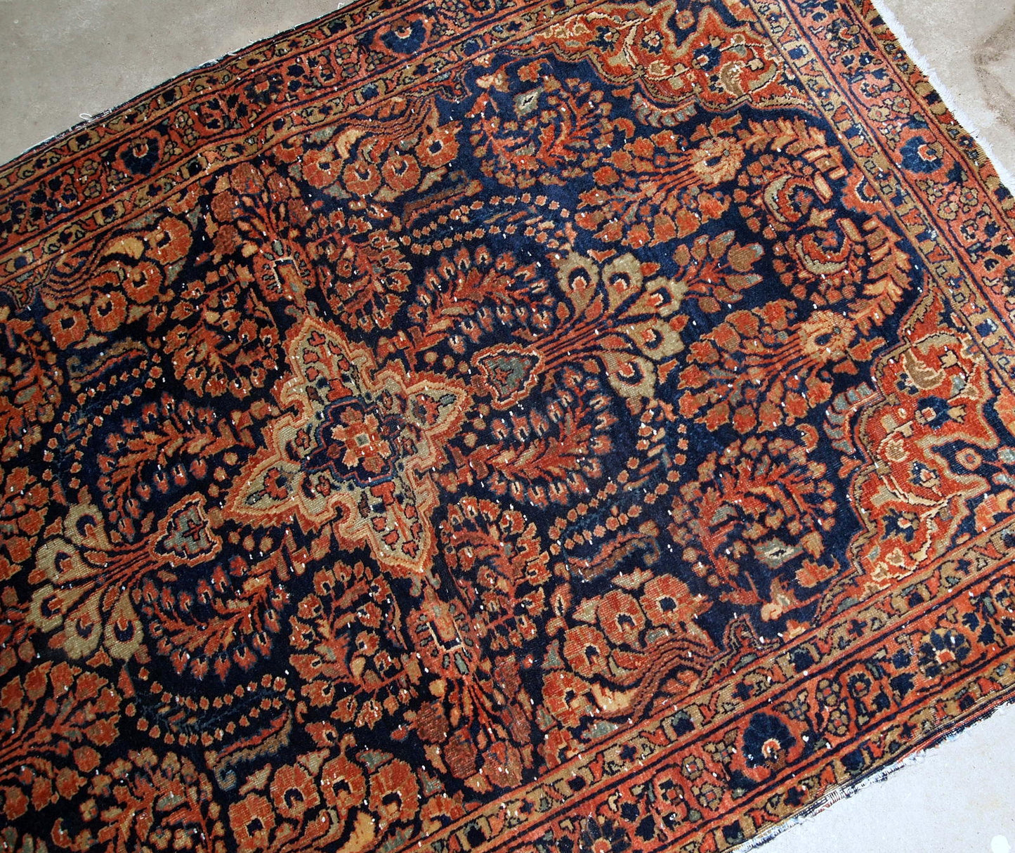 Handmade antique Persian Sarouk rug in original condition, it has some signs of age. The rug is from the beginning of 20th century made in red wool.