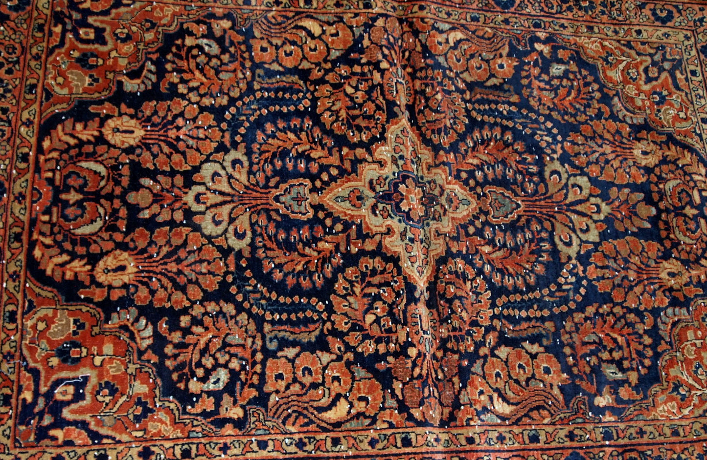 Handmade antique Persian Sarouk rug in original condition, it has some signs of age. The rug is from the beginning of 20th century made in red wool.