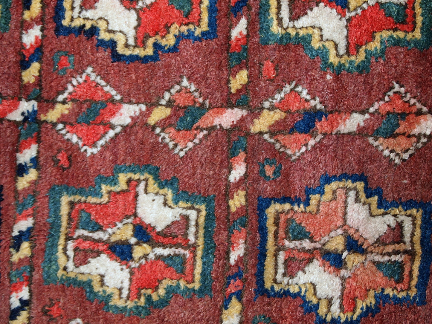 This antique Kurdish rug made in deep shade of burgundy. All-over design with geometric and tribal accents. The wool on the rug is soft, it is in original good condition.