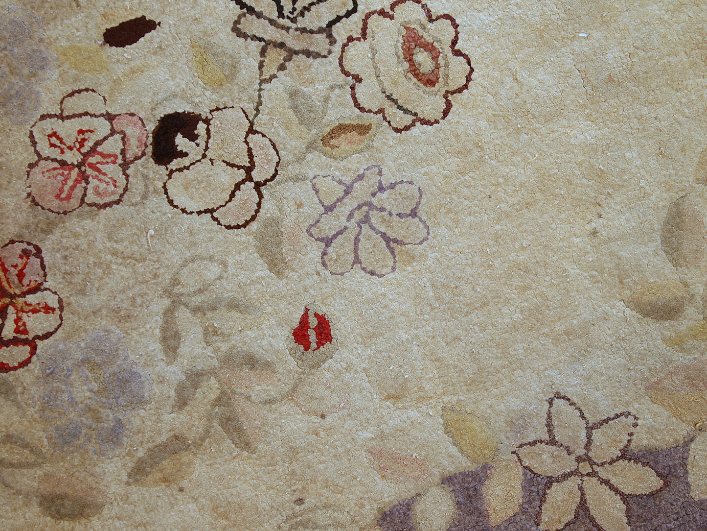 Handmade antique American Primitive Hooked rug in beige shade with abstract/floral design. The border is purple. It is in good condition.