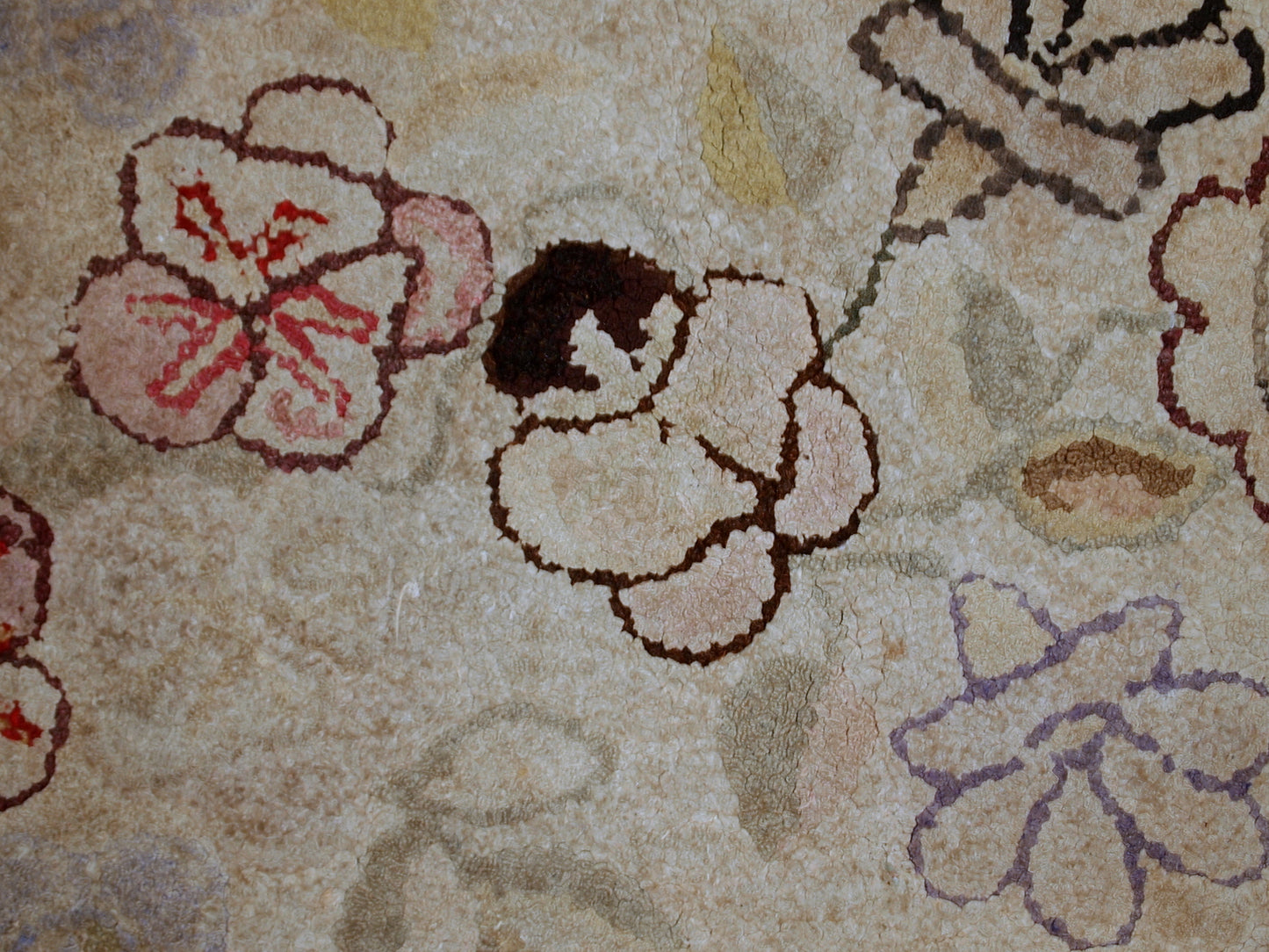 Handmade antique American Primitive Hooked rug in beige shade with abstract/floral design. The border is purple. It is in good condition.