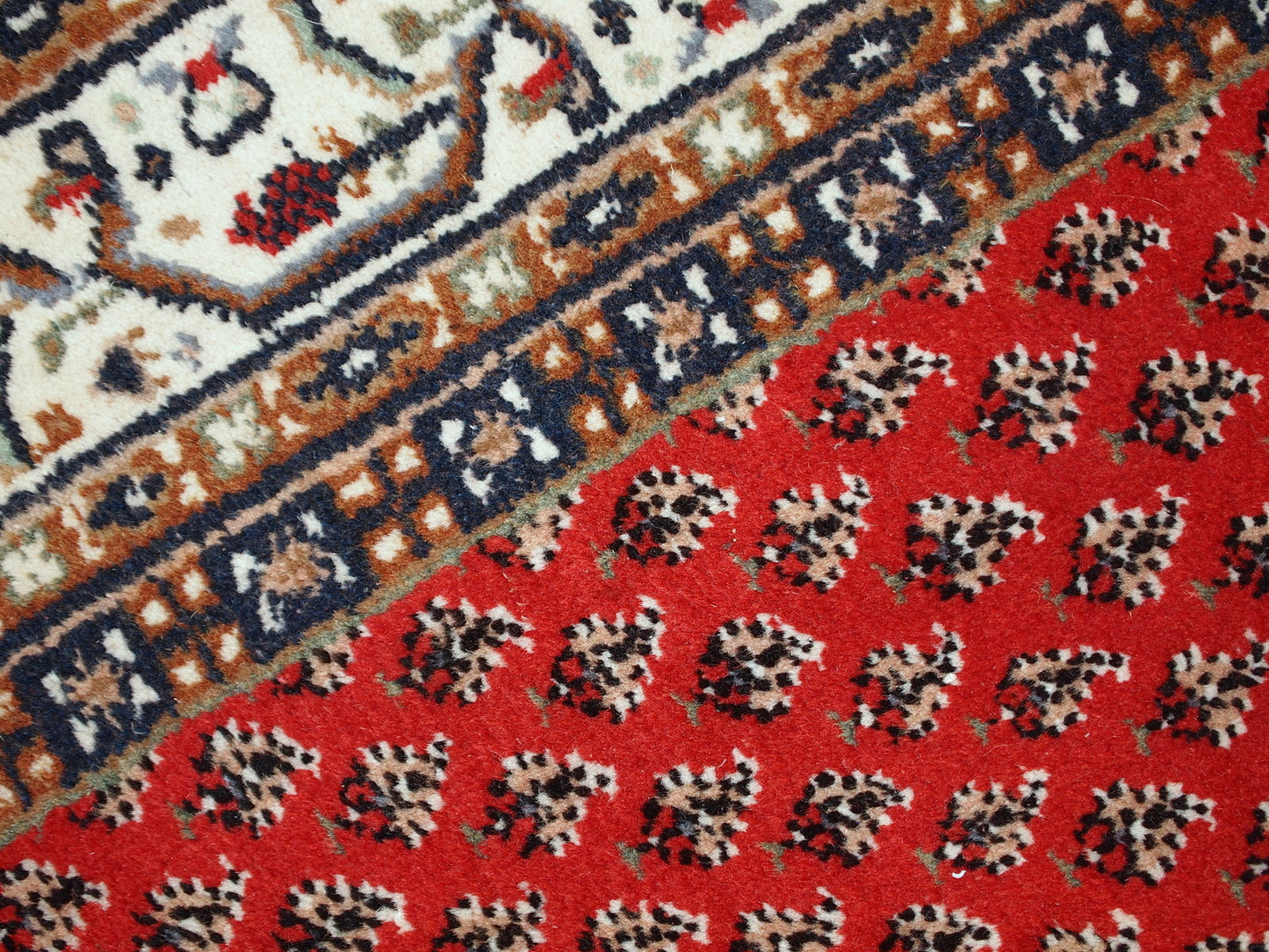 Vintage handmade Indian rug with Persian Seraband design in red with white border. All-over design with repeating pattern. The rug is from the end of 20th century in original good condition. 