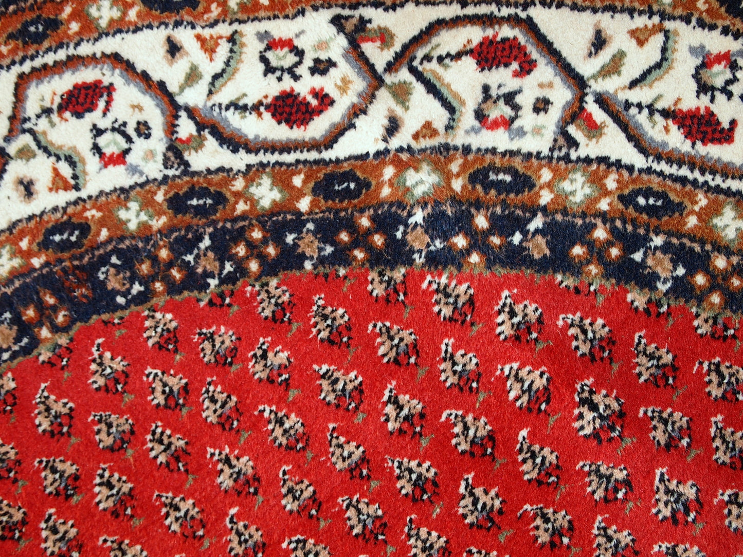 Vintage handmade Indian rug with Persian Seraband design in red with white border. All-over design with repeating pattern. The rug is from the end of 20th century in original good condition. 