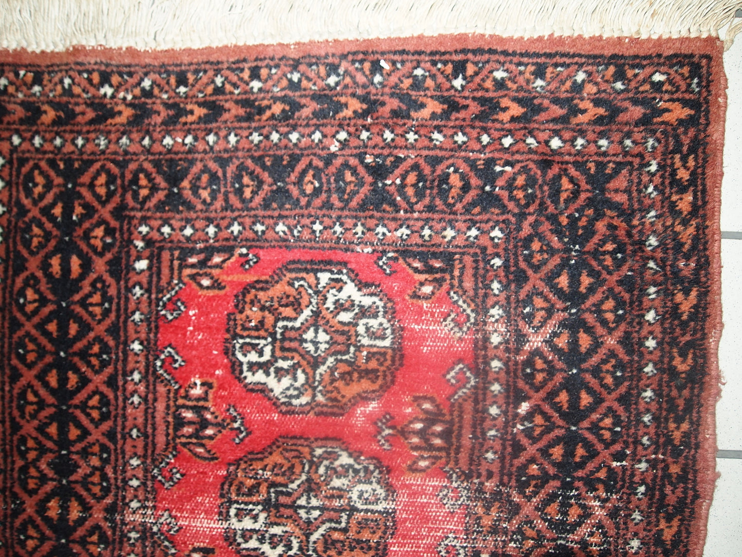 Vintage rug from Pakistan in distressed condition. The rug made in the end of 20th century in red wool.