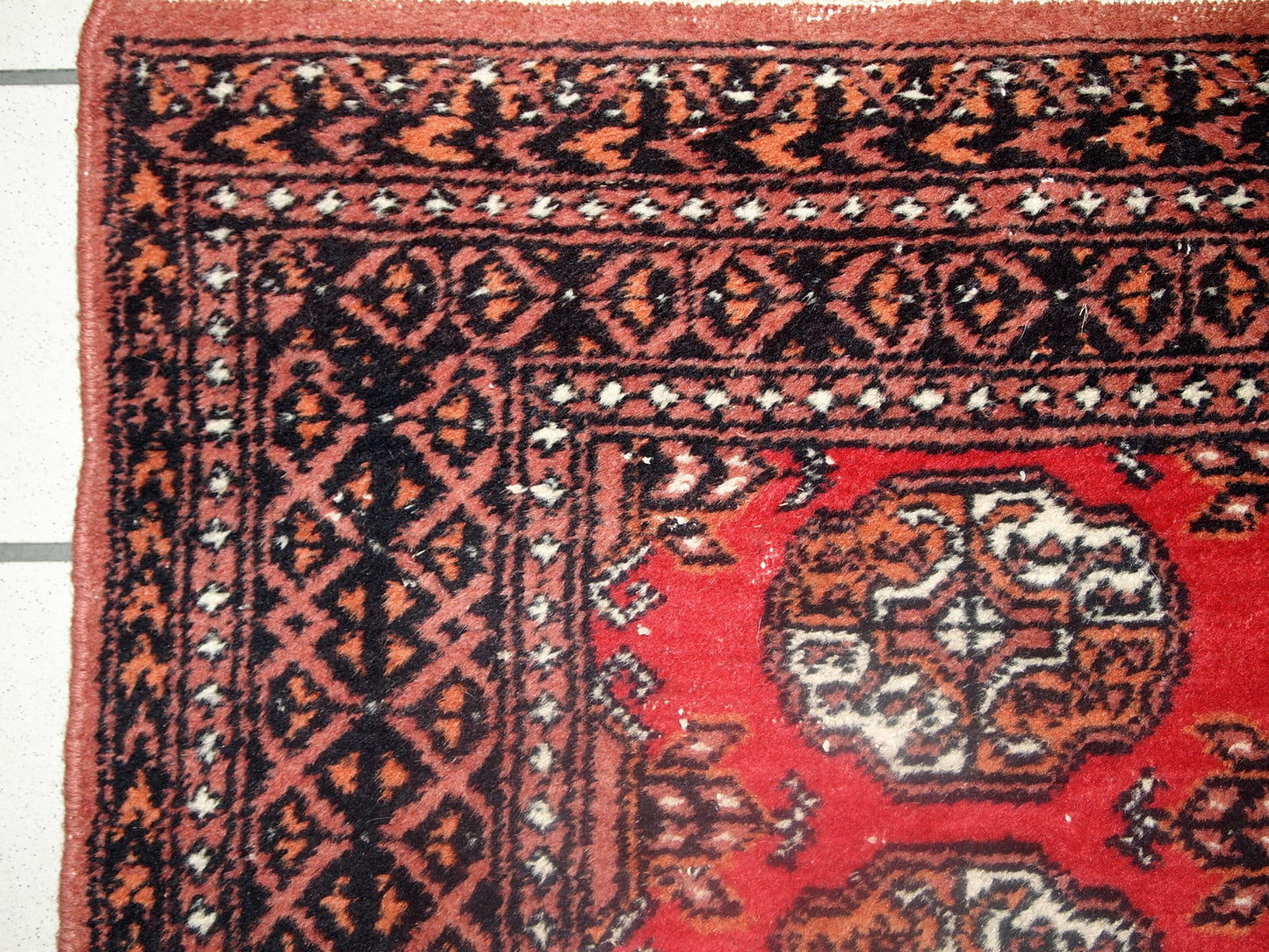 Vintage rug from Pakistan in distressed condition. The rug made in the end of 20th century in red wool.