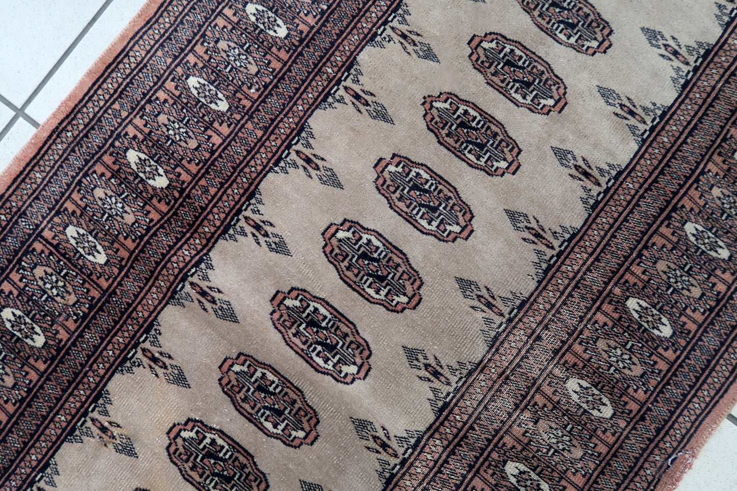Handmade vintage Uzbek Bukhara distressed runner in traditional design. The rug is from the end of 20th century made in wool.