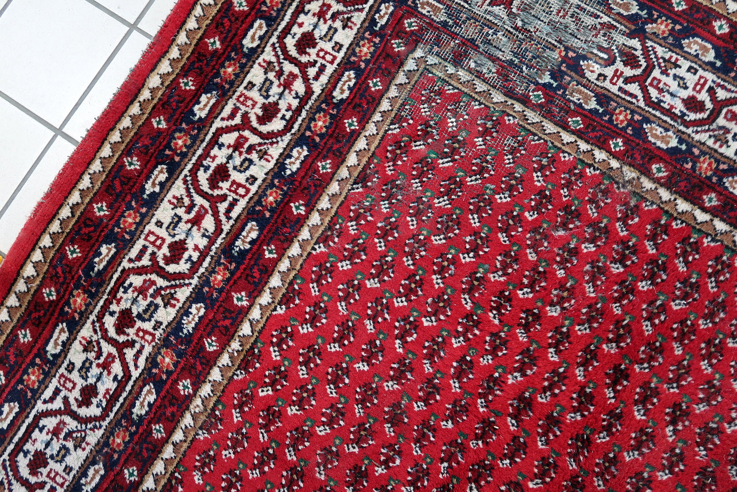 Handmade vintage Indian Seraband rug in original condition, it has some age wear on the one end. The rug has been made in traditional pattern, it is from end of 20th century. The shades of the rug are mostly in red and white. All-over design will bring some modern look to your space. All dyes on this rug are natural. This is the type of rug woven in India to compete in the same market as rugs from Persia.