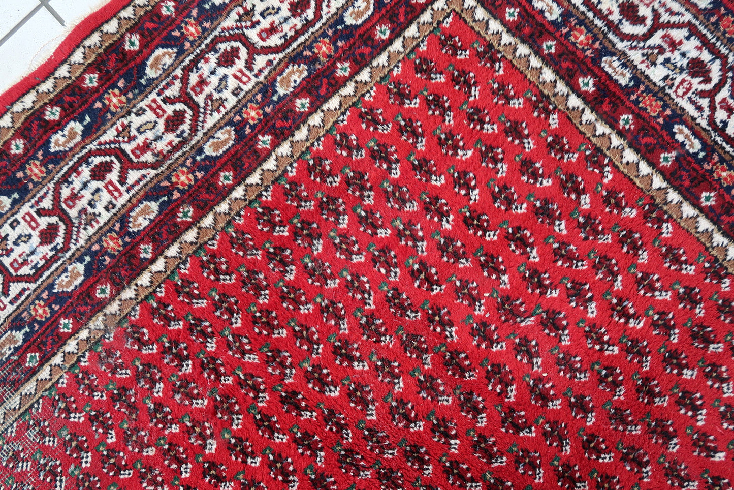 Handmade vintage Indian Seraband rug in original condition, it has some age wear on the one end. The rug has been made in traditional pattern, it is from end of 20th century. The shades of the rug are mostly in red and white. All-over design will bring some modern look to your space. All dyes on this rug are natural. This is the type of rug woven in India to compete in the same market as rugs from Persia.
