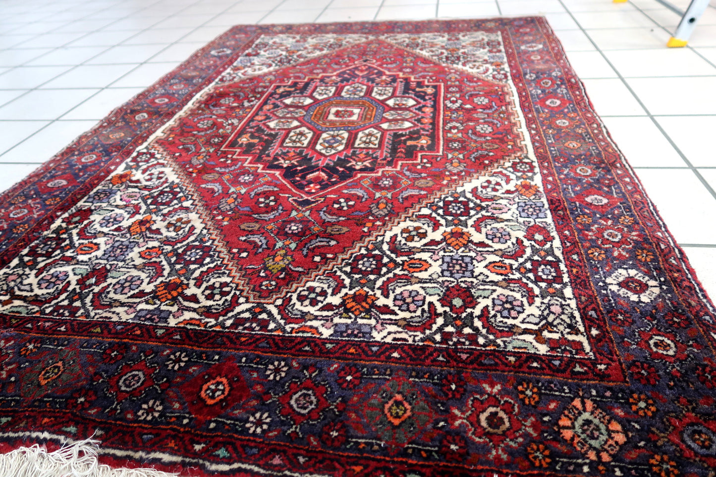 Handmade vintage Persian Bidjar woolen rug. The rug is from the end of 20th century, it is in original good condition. The rug is in traditional design with large medallion in the center. The color combination is white and red.