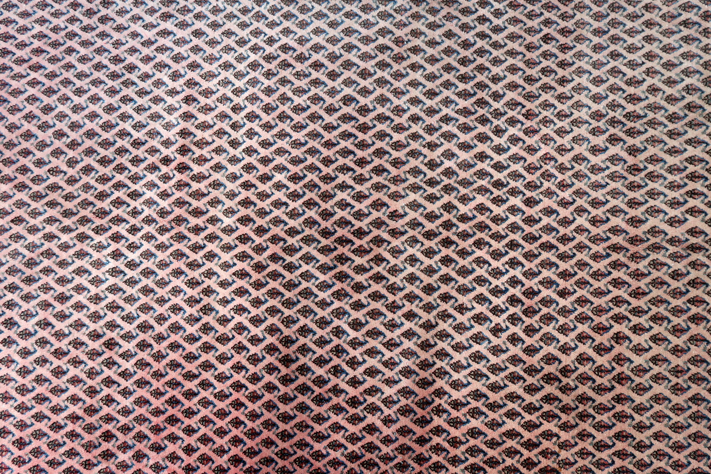 Handmade vintage Indian Seraband rug in original condition, it is unequally faded (one side is brighter then another) . The rug has been made in traditional pattern, it is from end of 20th century. The shades of the rug are mostly in pink and white. All-over design with repeating pattern. All dyes on this rug are natural. This is the type of rug woven in India to compete in the same market as rugs from Persia.