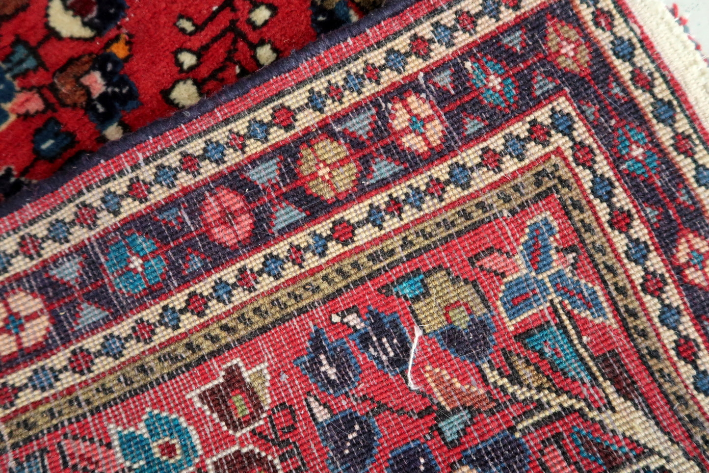 Handmade vintage Sarouk rug in traditional design. The rug is in red color. The rug is from the end of 20th century in original good condition.
