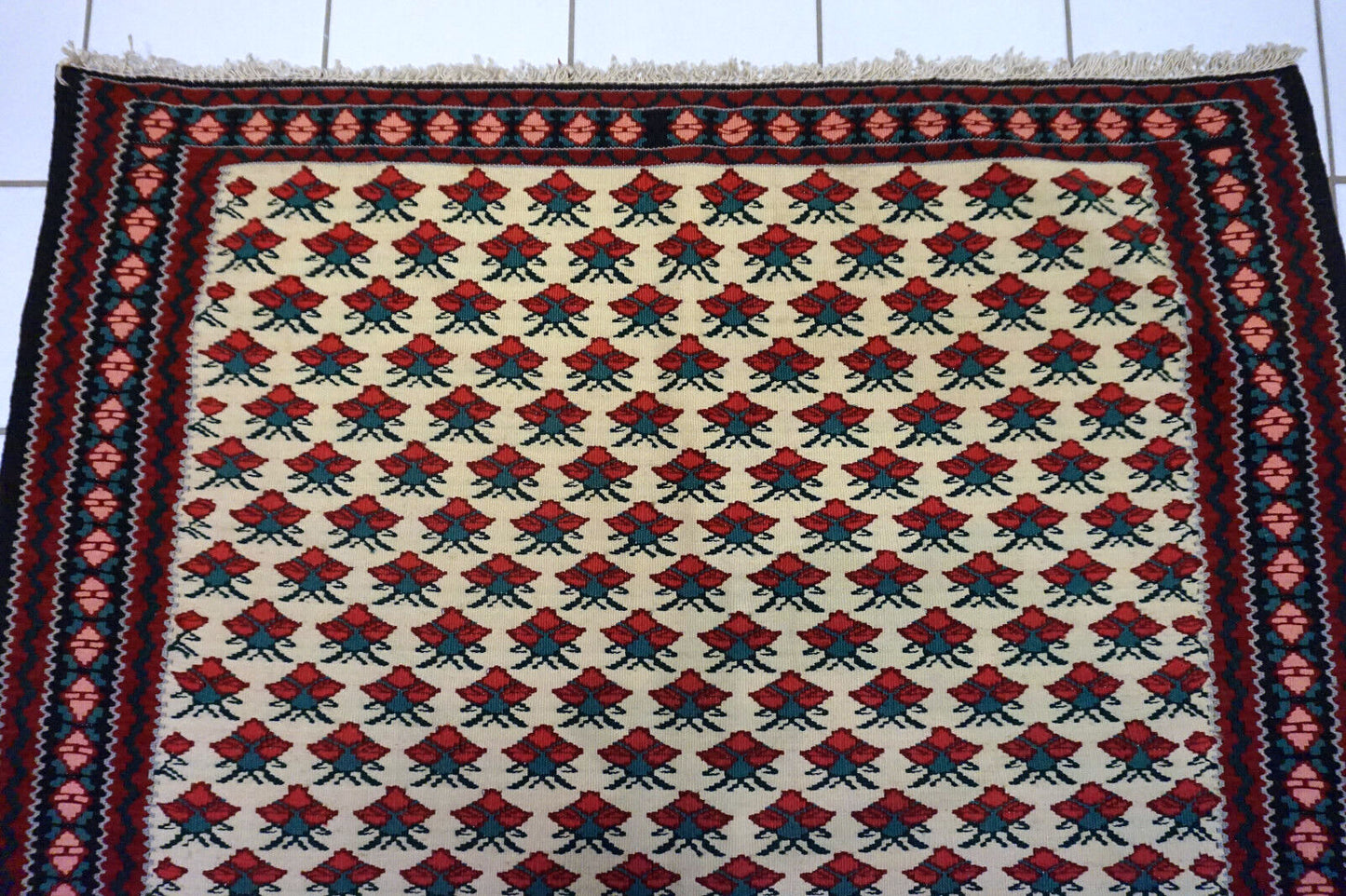 Close-up of vintage Ardabil kilim rug in beige, red, green, and black colors