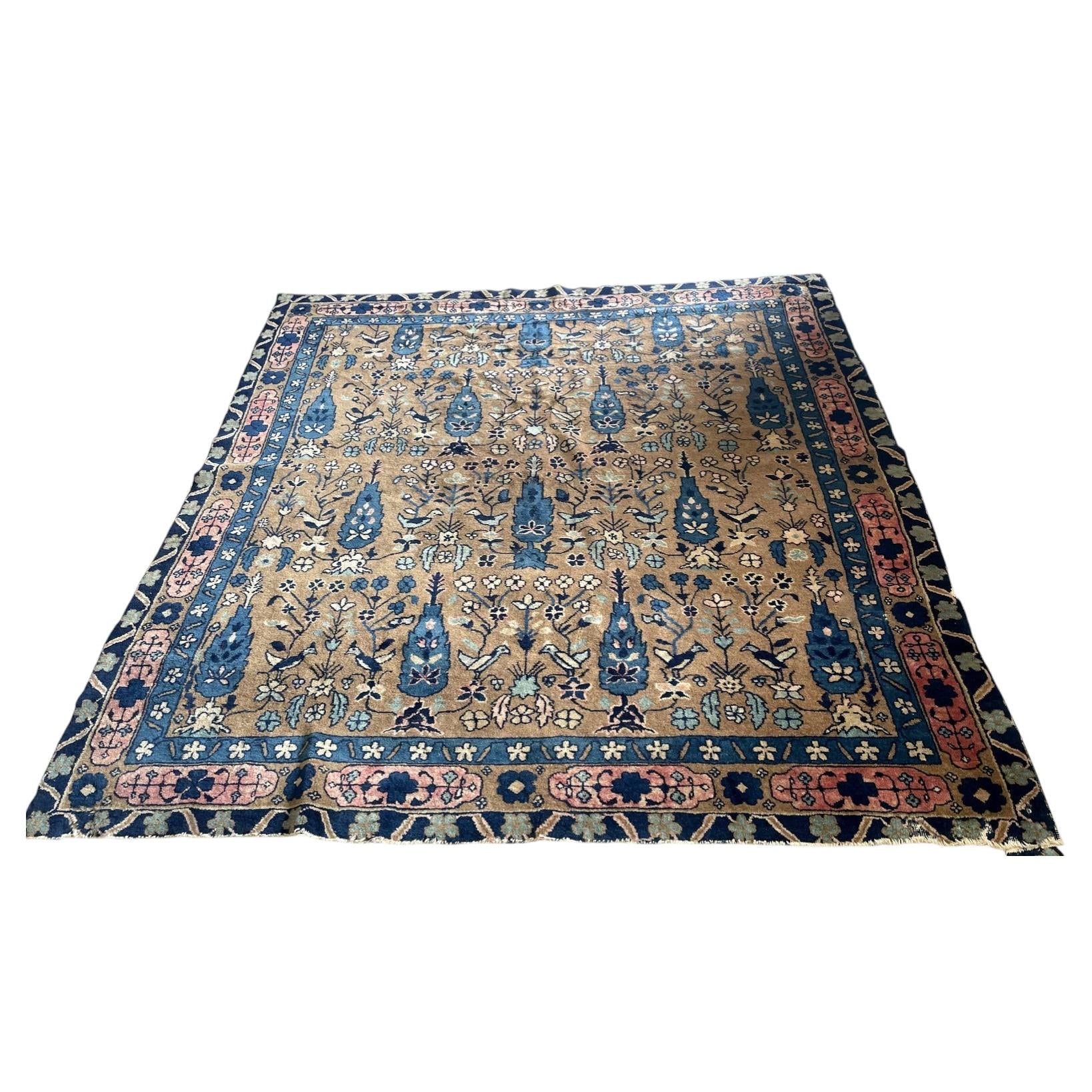 Full view of an antique Indian Agra wool rug from the 1880s featuring a warm golden tobacco field with an allover millefleurs garden scatter of cypress trees, flowering plants, and birds including white doves and songbirds.

