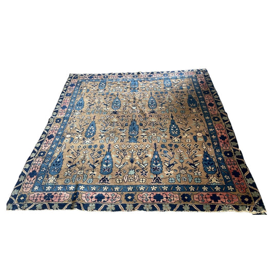 Full view of an antique Indian Agra wool rug from the 1880s featuring a warm golden tobacco field with an allover millefleurs garden scatter of cypress trees, flowering plants, and birds including white doves and songbirds.

