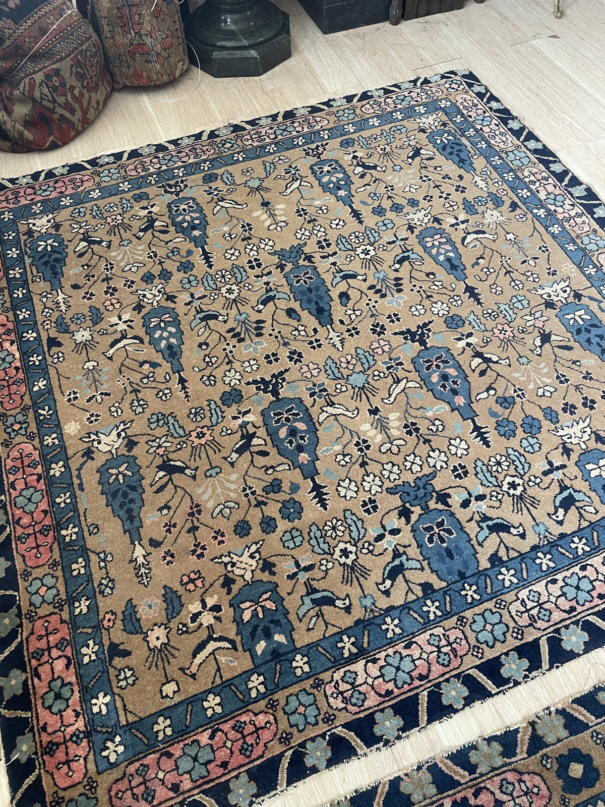 Close-up of the field on a vintage Indian Agra carpet showing cherry blossoms, four-petalled rosettes, clover forms, and delicate wildflowers rendered with botanical precision.

