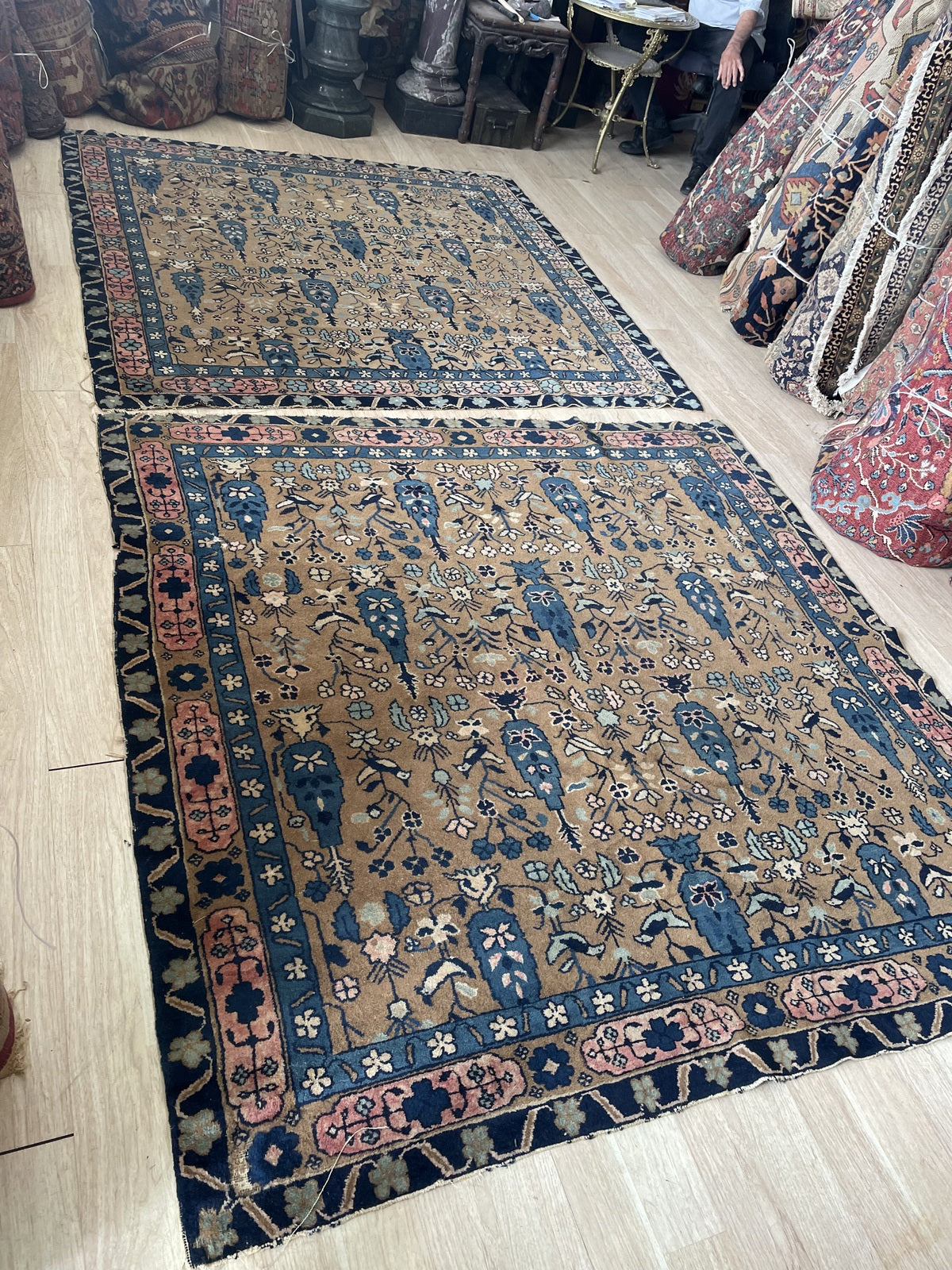Detail of the border system on an antique Agra carpet showing the wide midnight navy main border with large palmette blossoms, smaller rosettes, and a warm blush rose reciprocal floral guard border.

