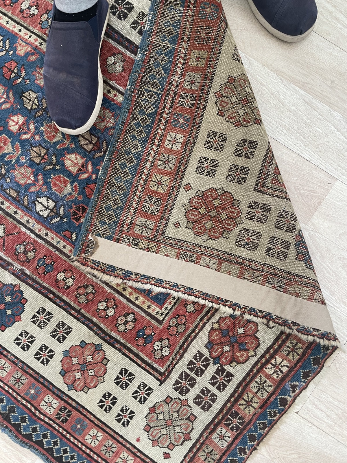 Detail of the teal-navy outer diamond reciprocal border on a vintage Talish rug, showing the crisp graphic element that anchors the composition and provides a strong visual terminus.

