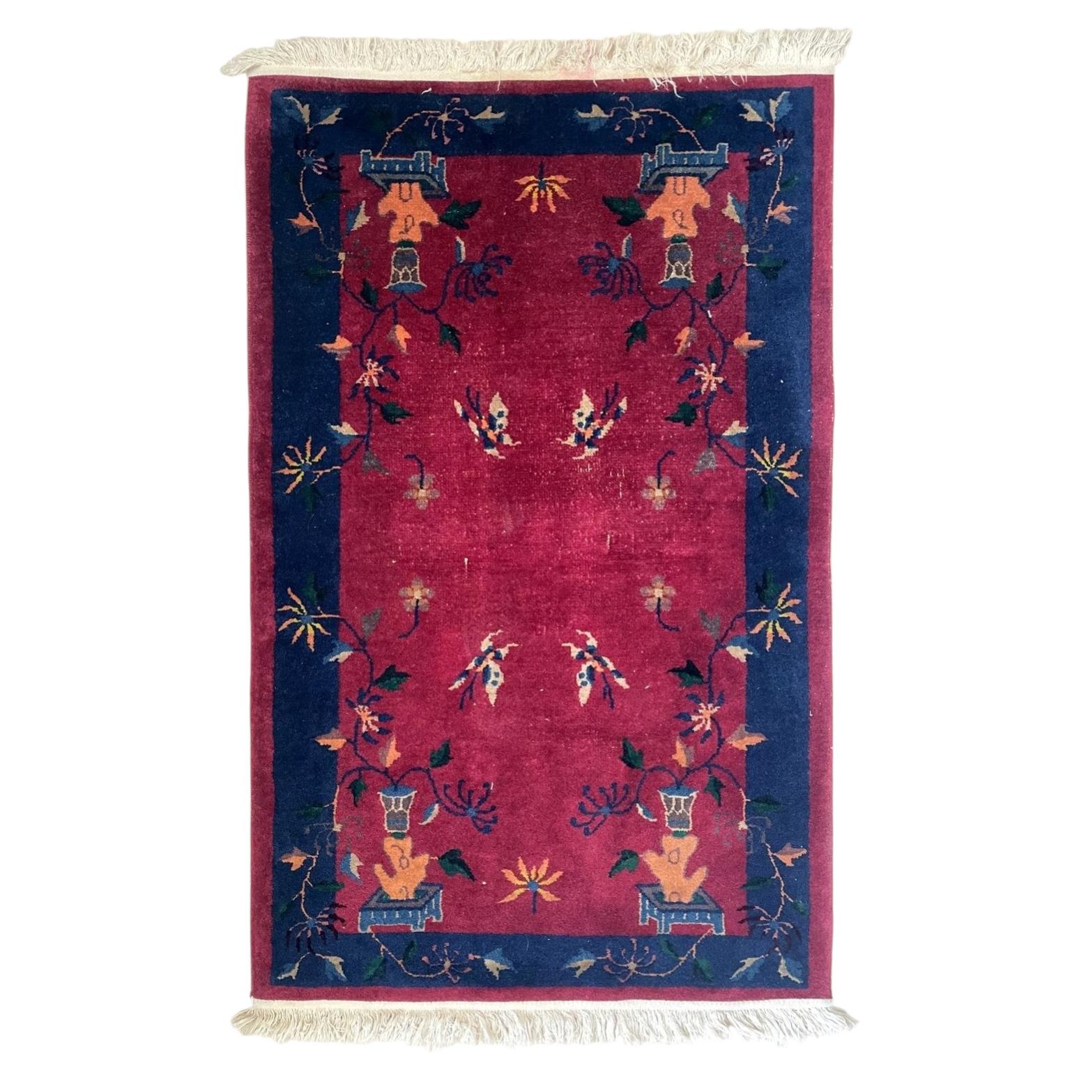 Full view of an antique Art Deco Chinese wool rug from the 1920s, featuring a deep luminous crimson ruby red field with two pairs of butterflies (húdié) in ivory, coral, teal, and gold, plus trailing vines, chrysanthemum and peony sprays, and maple leaf forms.

