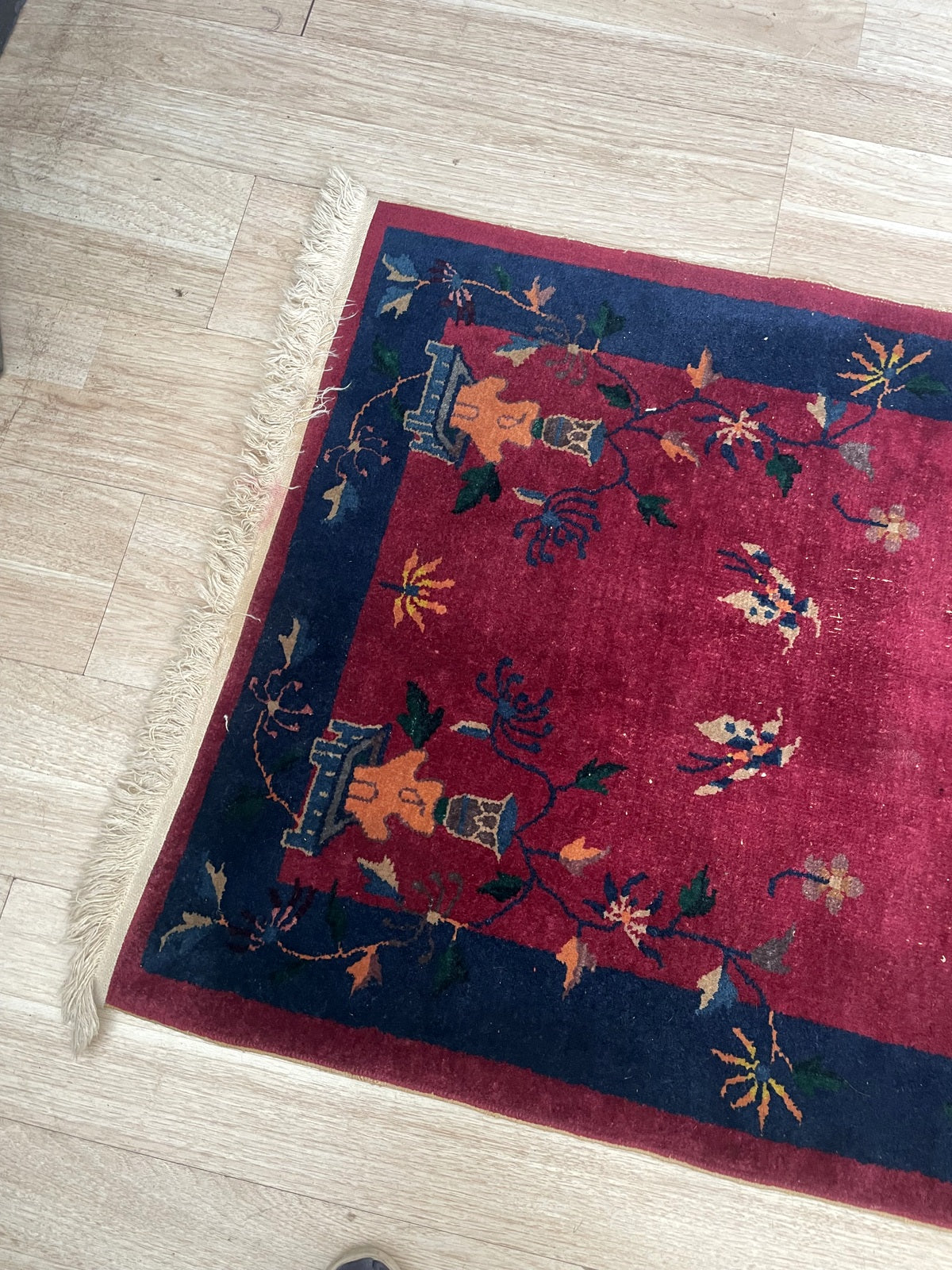 Full view of a circa 1920s Chinese Art Deco accent rug with a deep crimson field, scattered butterflies, trailing vines, peonies, chrysanthemums, and maple/palm leaves in navy, saffron, forest green, and ivory.

