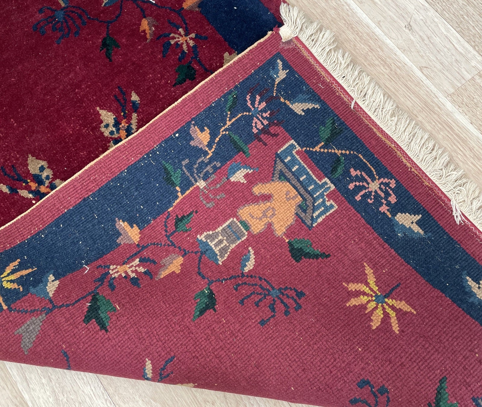 Detail of a butterfly pair on a vintage Chinese Art Deco carpet, rendered in teal and gold against the ruby red ground, symbolizing joy and conjugal happiness in Chinese poetic tradition.

