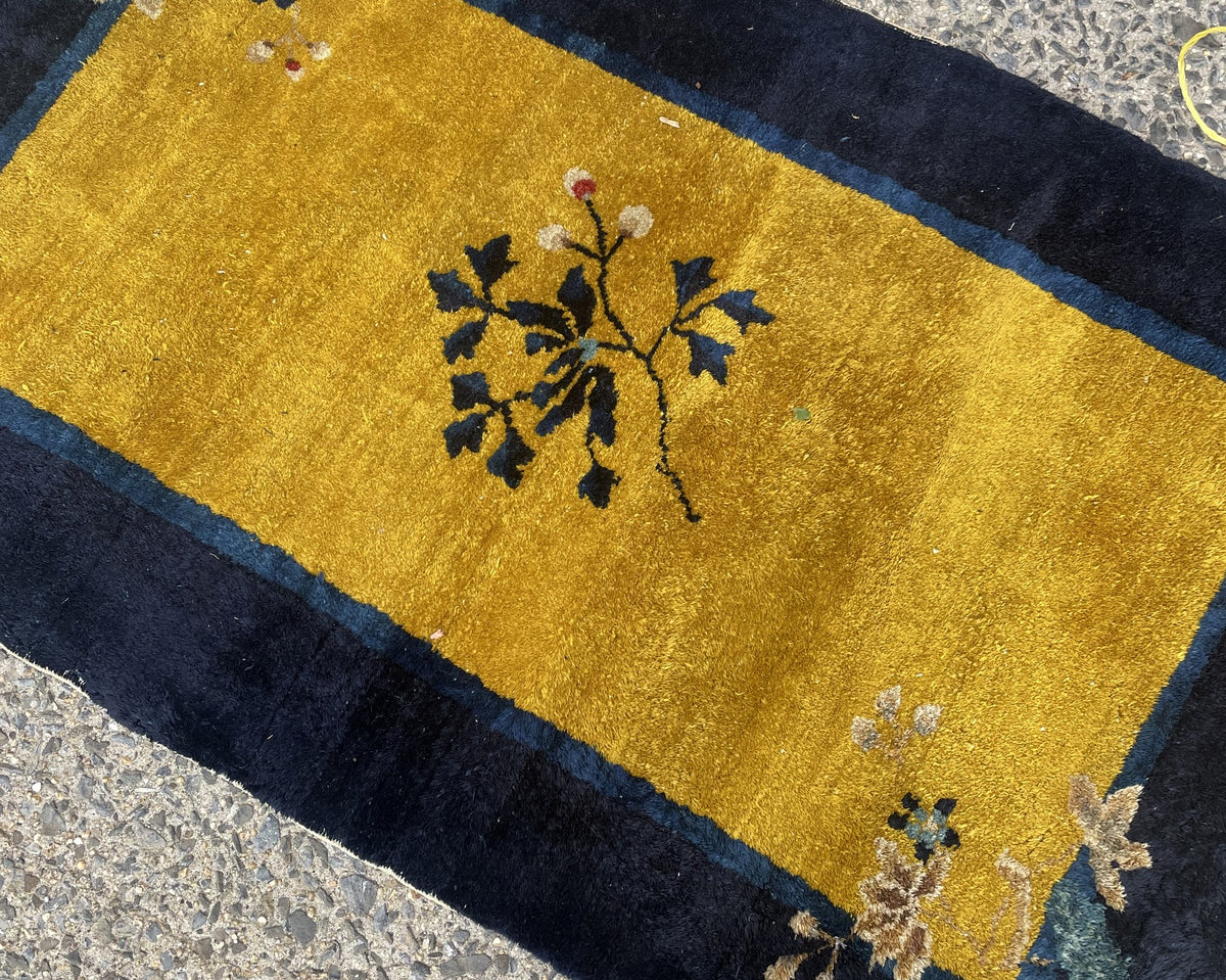 Navy border, golden field and fringed end of antique Chinese wool rug