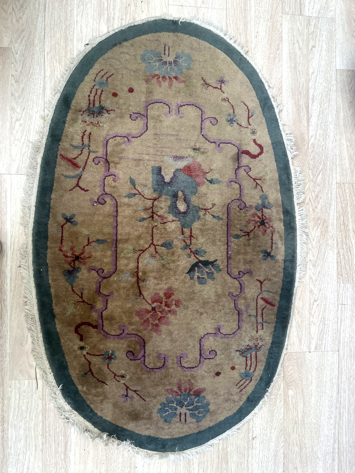 Oval floral rug with lilac scrollwork and uneven light perimeter fringe