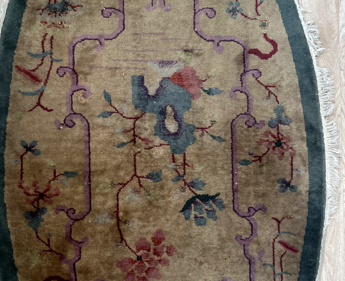 Central floral arrangement, lilac frame and visible wear on antique wool rug