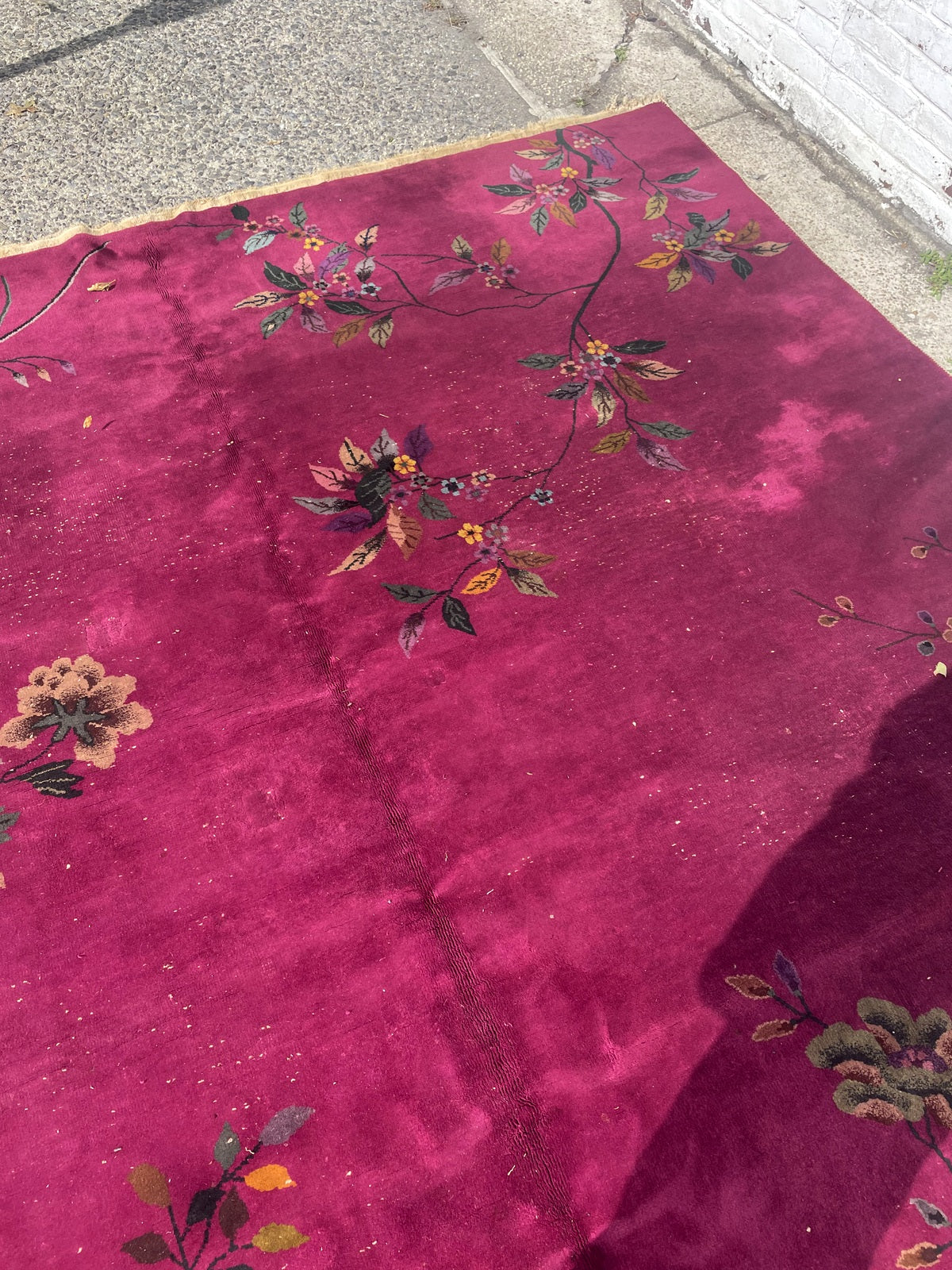 Curving floral branches framing a broad open section of the magenta rug