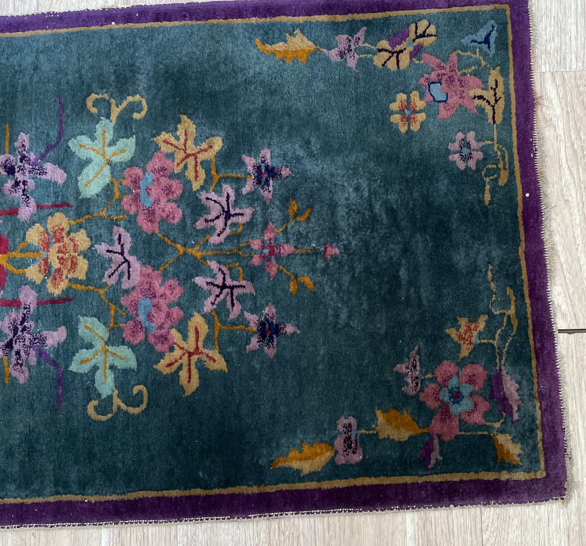 Close-up of pale green, lilac and pink flowers against shaded teal wool