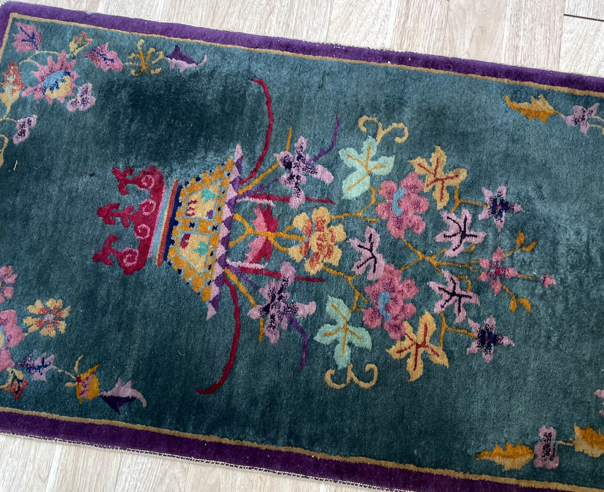 Golden-yellow floral vessel on a raspberry-red scrolling stand