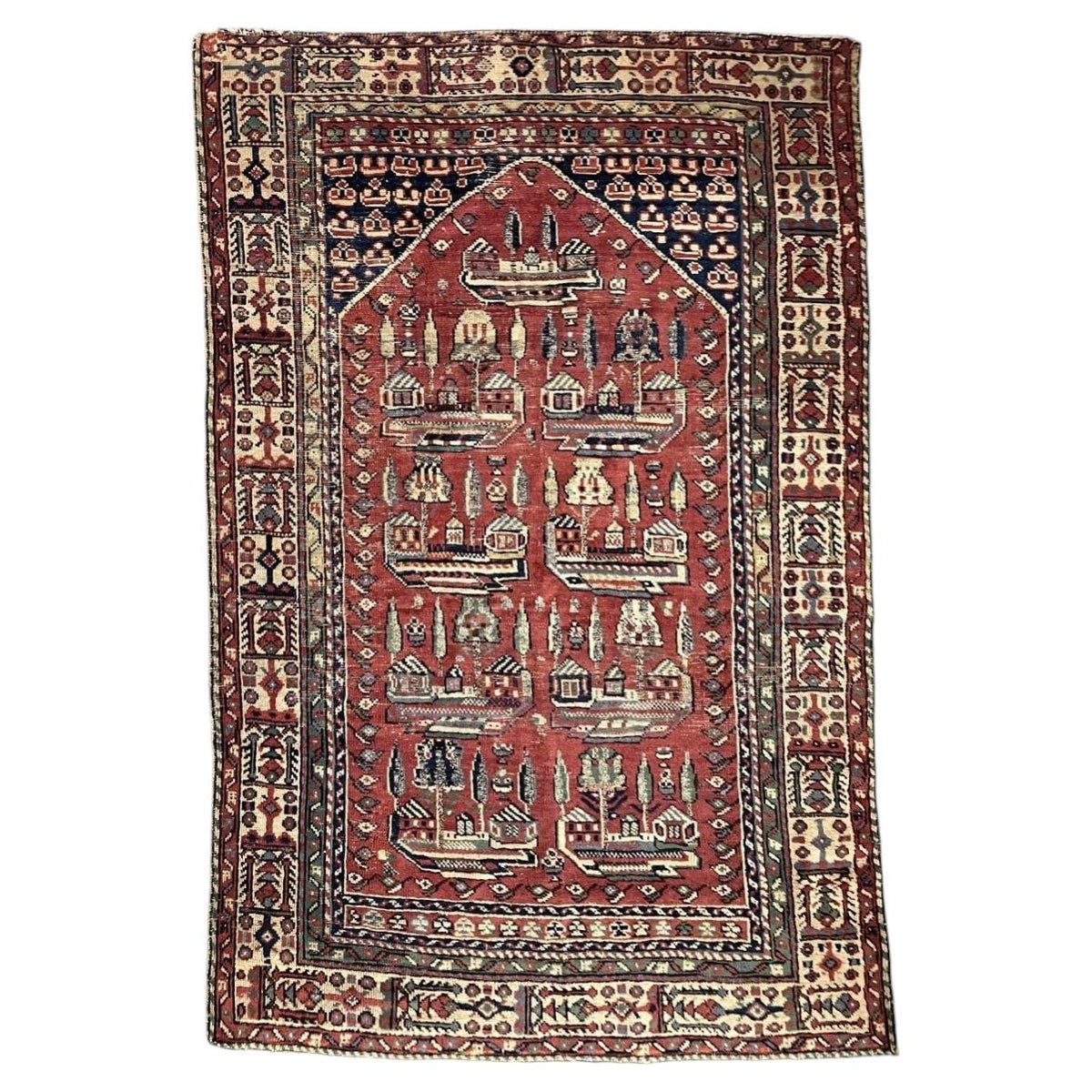 Antique Turkish Ghiordes wool rug with red architectural field and ivory panelled border
