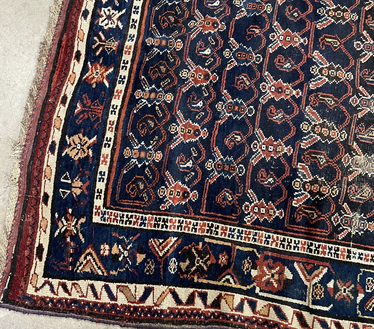 Worn antique wool rug with exposed foundation and patterned blue borders