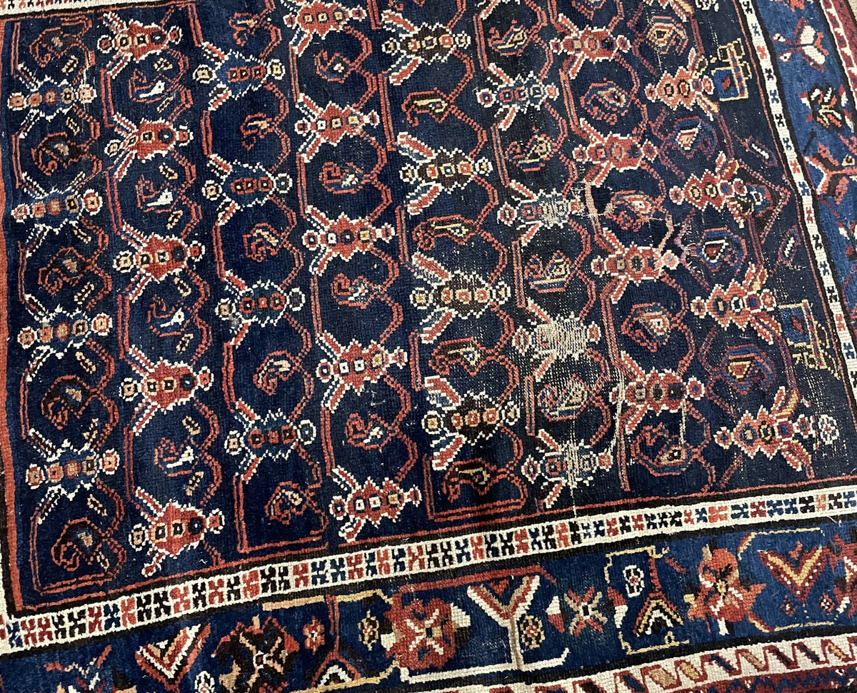 Floral lattice field with pronounced worn patches and pale exposed foundation